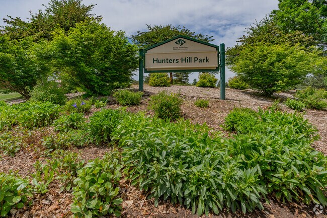 Park signage in a garden at Hunters Hills Park is surrounded by lots of foliage.