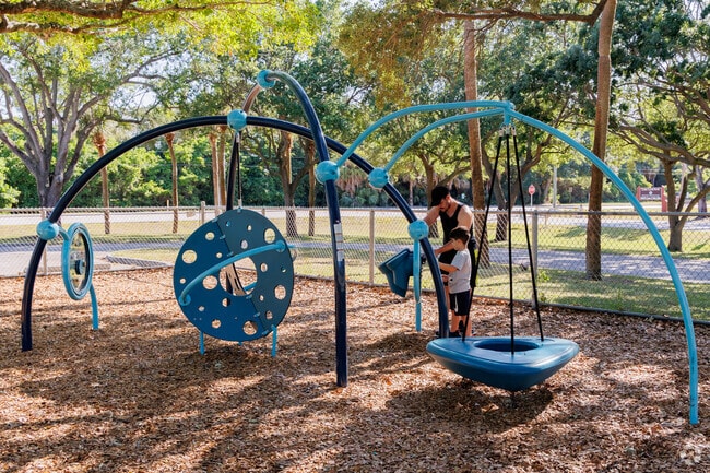 Royal Palm Estates father watching over his son enjoying the playground at Lytal Park.