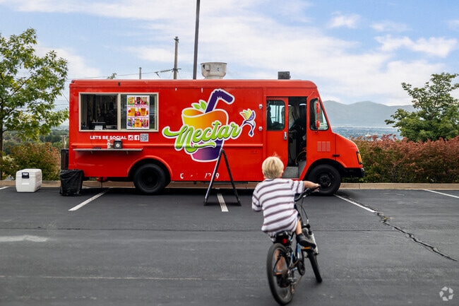 A boy rides his bike in front of a red food truck.