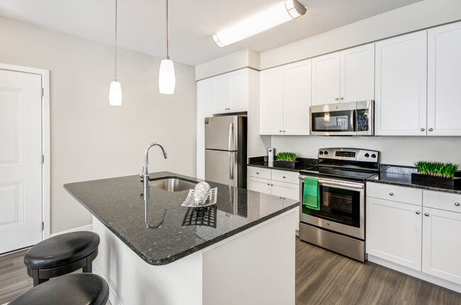 Kitchen with granite countertops, white shaker cabinetry, stainless steel appliances, kitchen island and hard surface flooring