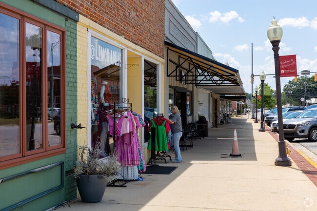 Shoppers explore street-side fashion displays along a retail strip.