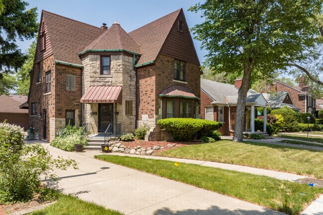 Tudor-style brick home with a stone-detailed entry sits among trees in Dearborn's Aviation neighborhood.