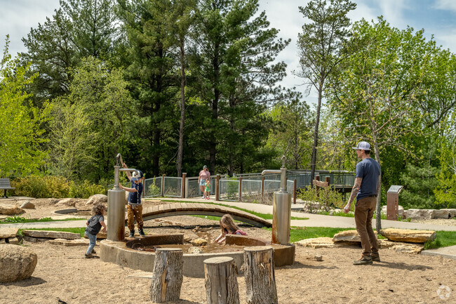 Families enjoy a natural play area equipped with water pumps at Whitetail Woods Regional Park.