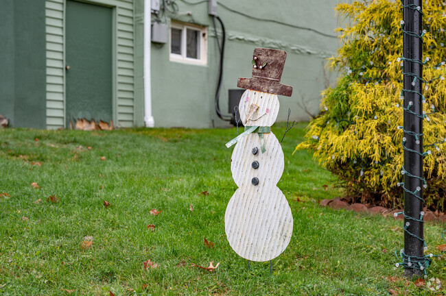 A small homemade snowman sits beside a light pole in a front yard in Washington.