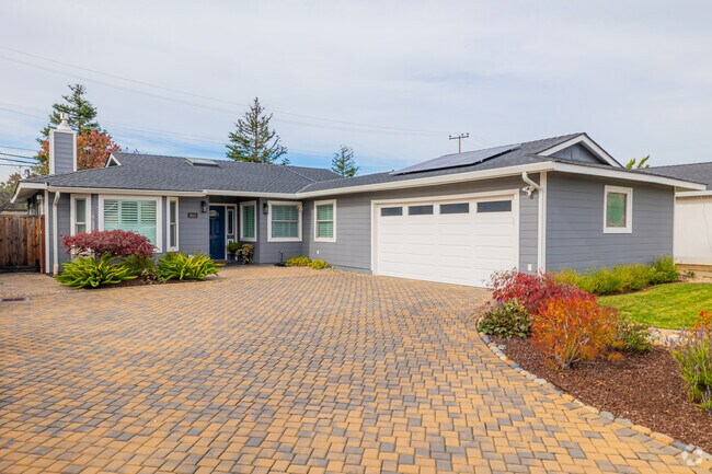 A grey ranch-style home in Los Prados has a masonry driveway.