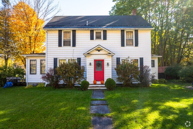 A colonial style home has a red door and black shutters in Fairfax Village.