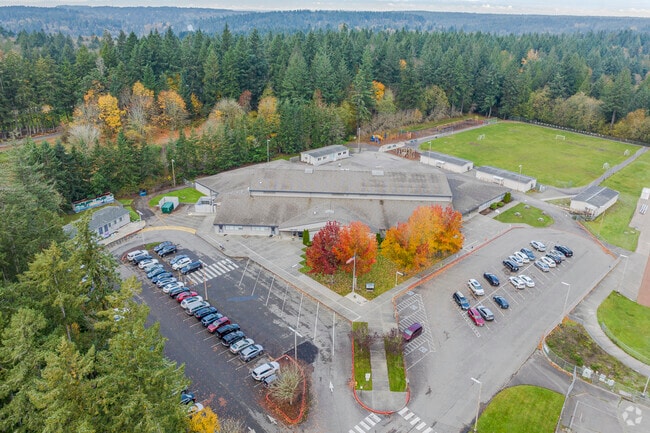 Higher Aerial to show overall campus. behind massive tree-line.