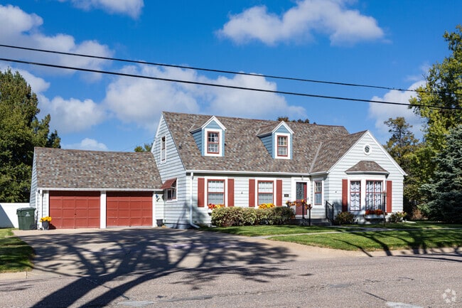 A tidy cottage in Minden pairs shutters and dormers with a shaded lawn.