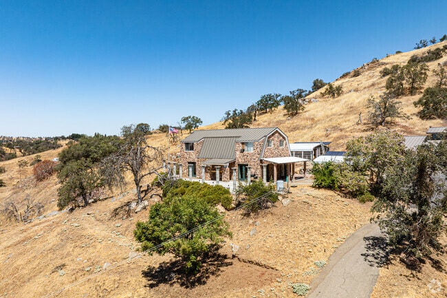 A stone home sits amid Yokuts Valley’s dry hills and sparse Sierra Nevada vegetation.