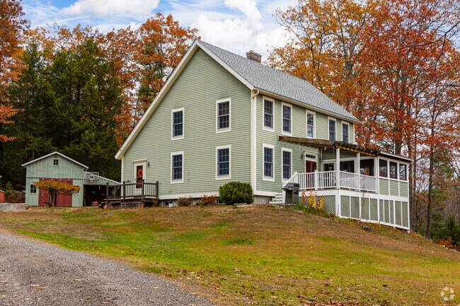 A saltbox-style home sits amid Tuftonboro’s vibrant fall foliage.