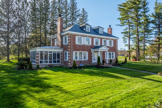 A brick foursquare style home with a screened-in porch in Winchendon has a large yard.