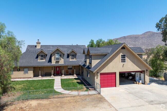 Charming home with red garage door, manicured lawn, and mountain backdrop.