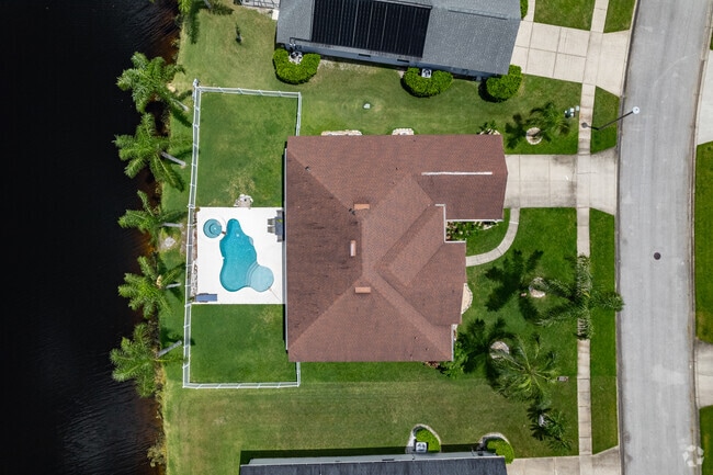 An aerial view of a waterfront home with an expansive yard in Waters Edge.