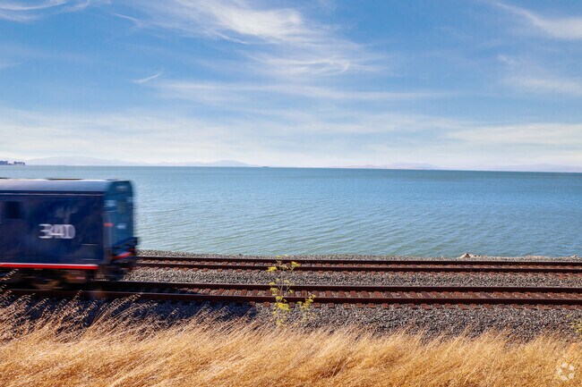 A whisper quiet Amtrak train 
crosses the waterfront in hourly in Gateley.