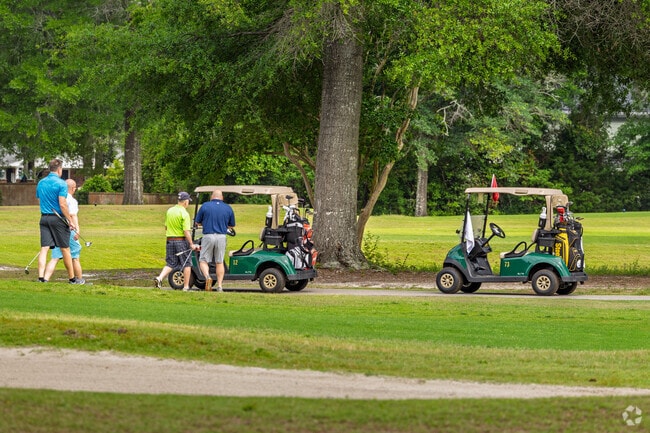 Golfers enjoy a sunny day on the course at Grande Dunes with carts and tree-lined fairways.
