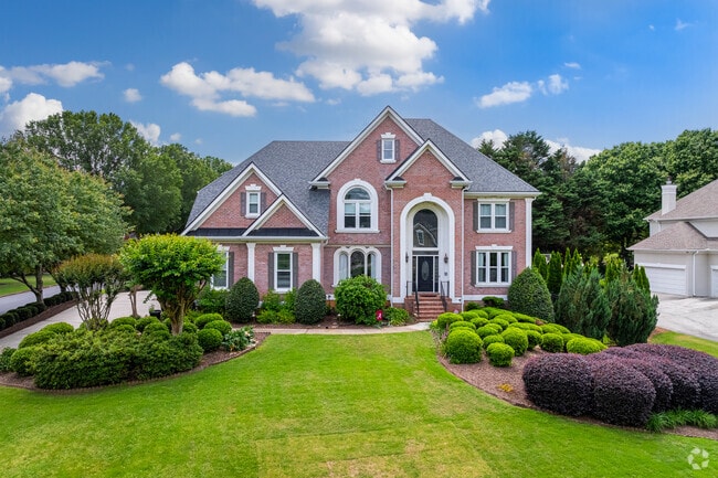 Several houses in Seven Oaks are known for their curb appeal like this traditional style home featuring a symmetrical design, manicured lawn, and mature landscaping.