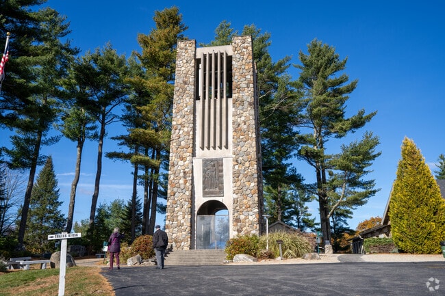 Visitors approach the stone bell tower at the Cathedral of the Pines in Rindge.