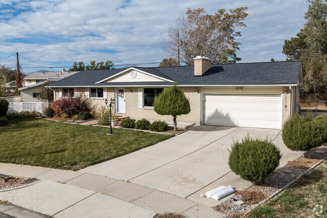 With a nicely landscaped yard this cream and white home with a black roof is a lovely house.