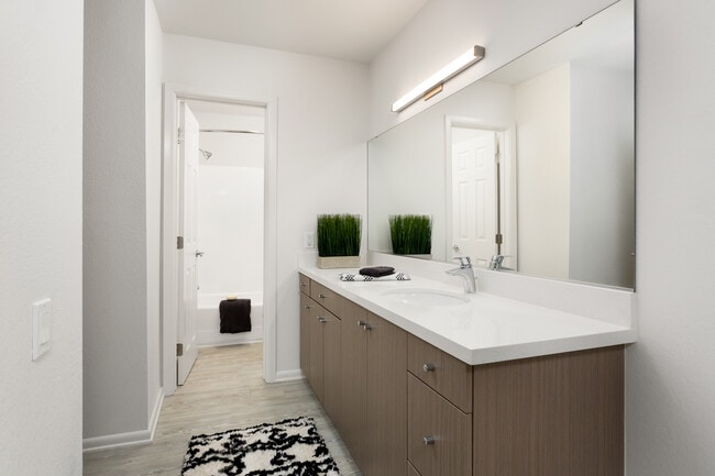 Renovated Package II bath with tan cabinetry, white quartz countertops, and hard surface plank flooring