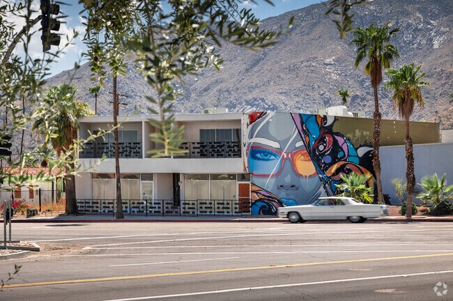 A classic car drives by a mural located in the Racquet Club West neighborhood.