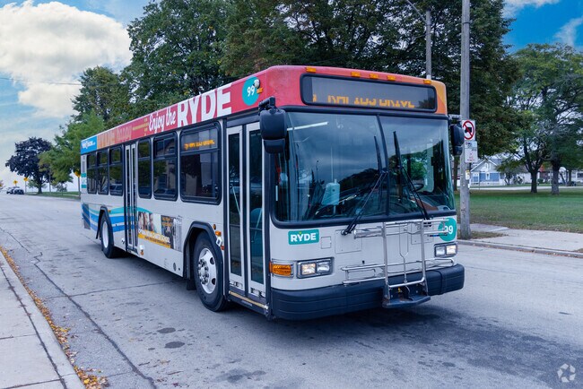 A white RYDE bus with colorful decals stops on an autumn day in Eagle Lake.