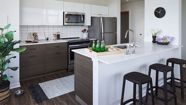 Apartment Kitchen with Stainless Steel Appliances, quartz counters and wood floors.