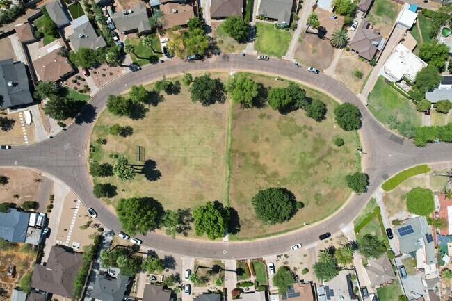 The Country Club Oval Park in is a large grass field with trees along its edges.