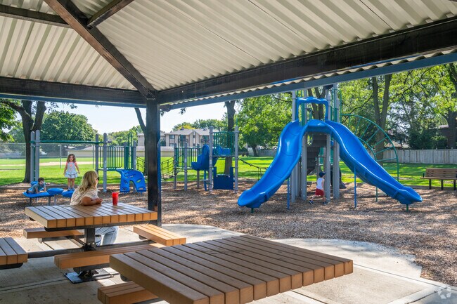 A mother watches her kids play under the shade of a picnic area at Pembroke Park.