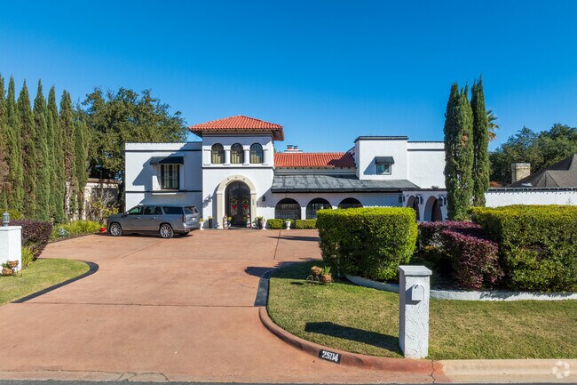 This elegant Onion Creek home features a terracotta roof and manicured landscaping.