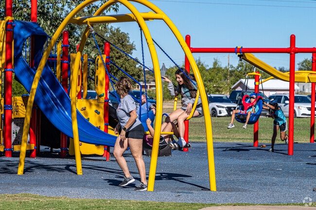 Parents and children enjoy the playground at Unidad Park in San Angelo, Texas.