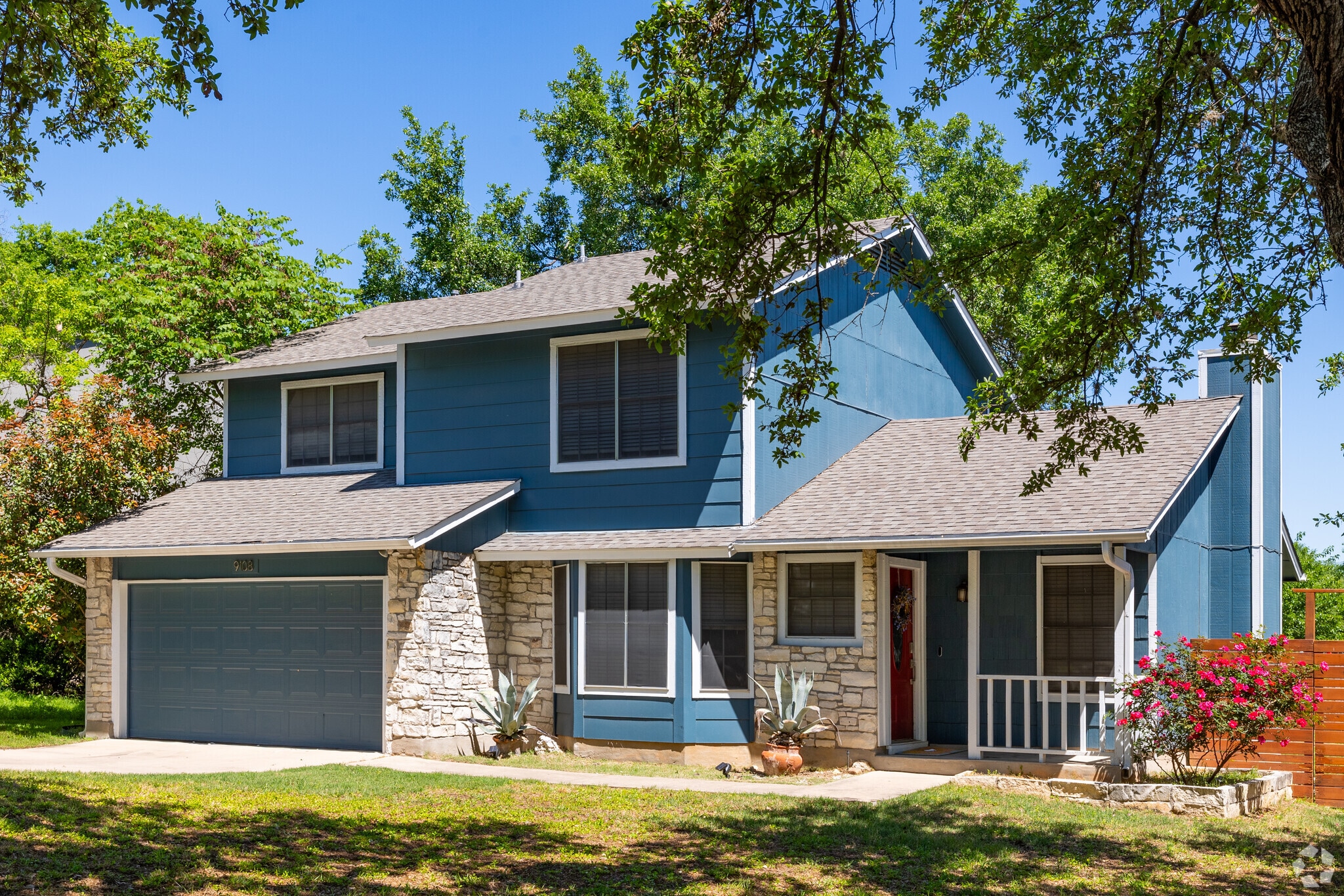 A national style home under a shaded oak tree located in South Austin.