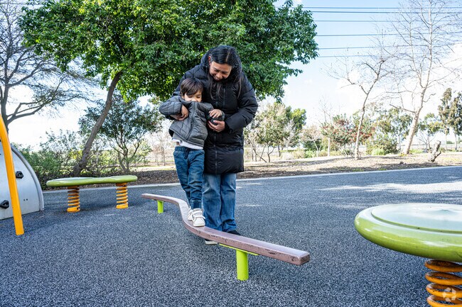 A mother leads her son on a balance beam at Hollydale Regional Park in Downey, California.