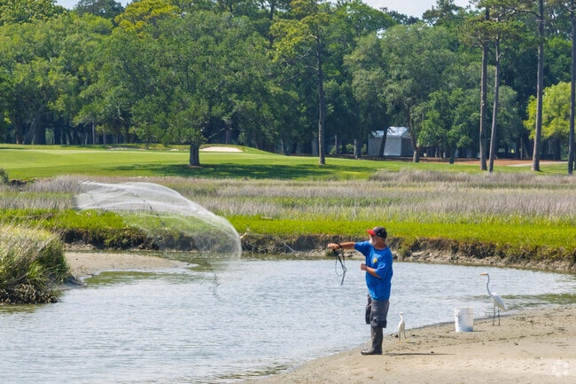 A fisherman casts a net in the marshland bordering Arcadian Shores.