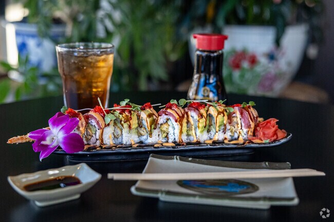 A colorful sushi platter garnished with a purple and white orchid.