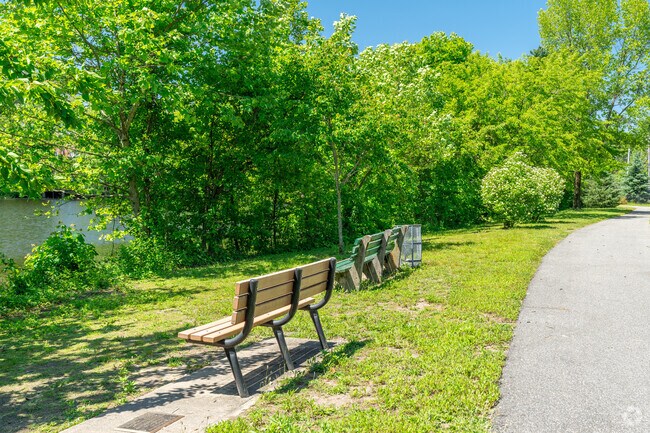 The walking paths of Herricks Park are tree lined with benches overlooking the pond.