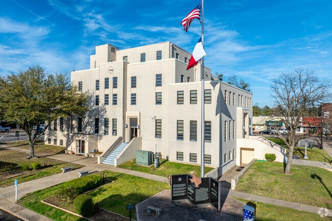 The iconic Titus County Courthouse in Mount Pleasant stands tall, with the American and Texas flags flying proudly and surrounded by murals and monuments that celebrate local history.