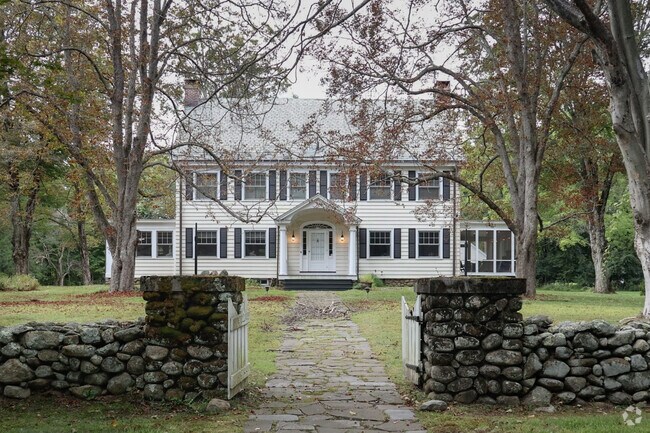 A stone wall and gated entrance add additional charm to a gorgeous Colonial home.