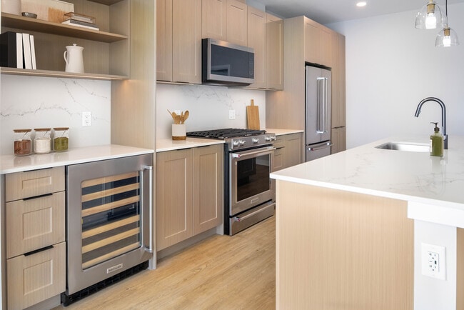 Signature Collection Kitchen with oak shaker cabinetry, marbled white quartz countertop, and upgraded stainless steel appliances