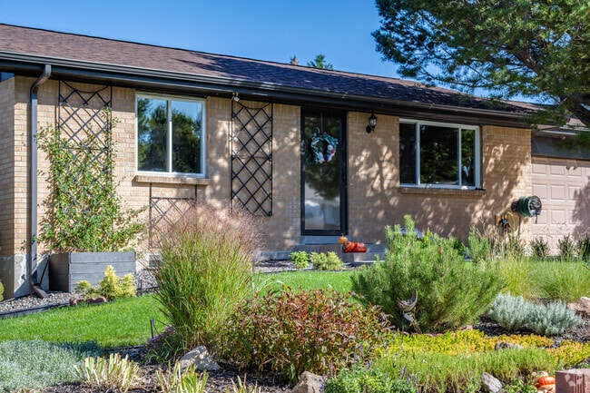 A ranch home with light colored brick and a lush front garden in Parkway Estates, Arvada, Colora