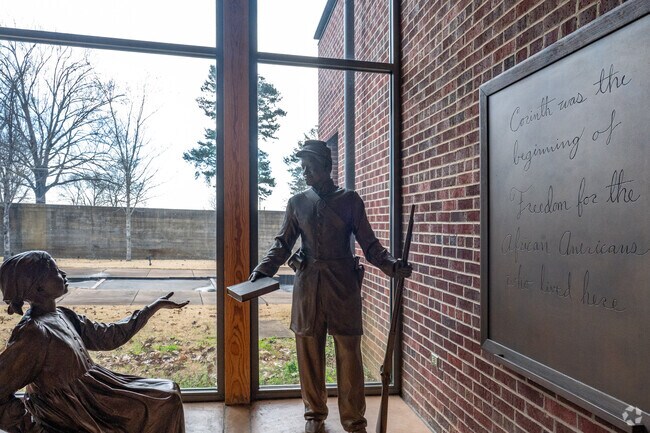An art installation at the Corinth Interpretive Center of Shiloh National Military Park depicts a northern soldier handing a book to an African American after they captured the city.