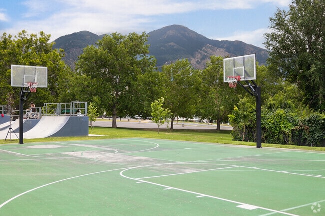 Basketball courts surrounded by trees with mountains in the background at North Ogden Park.