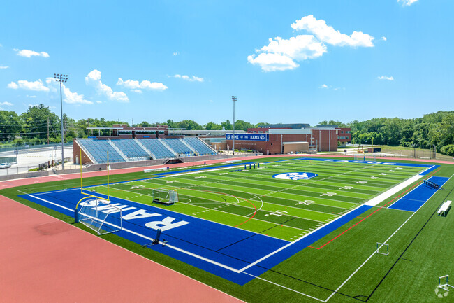 Football field from corner of endzone showing main bleachers and athletic complex building.