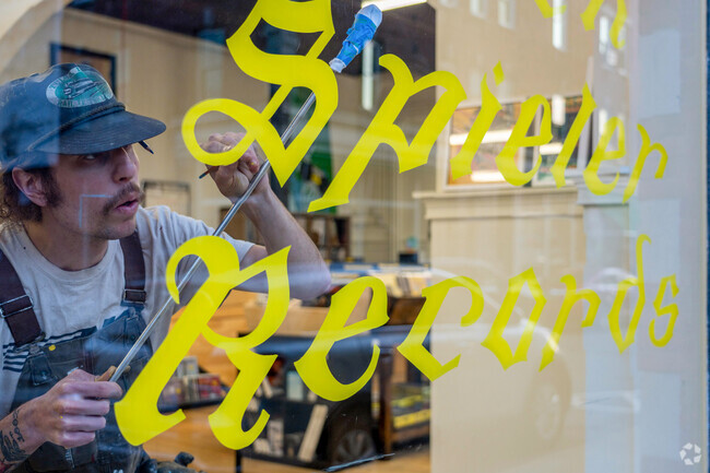 A painter adds the finishing touches to the Buch Spieler Records window sign near Park West.