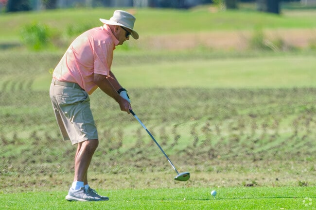 A resident tees off on a splendid day to enjoy a round of golf.