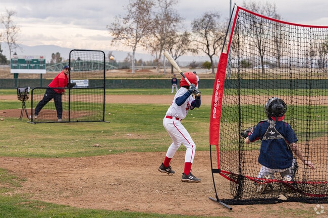 The coach pitches to his player during practice at Aera Park.