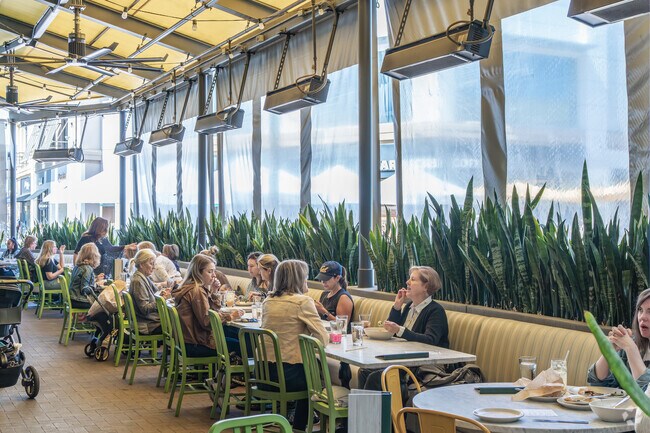 Groups of people enjoy dining in the covered patio at True Food Kitchen in Broadway Plaza.
