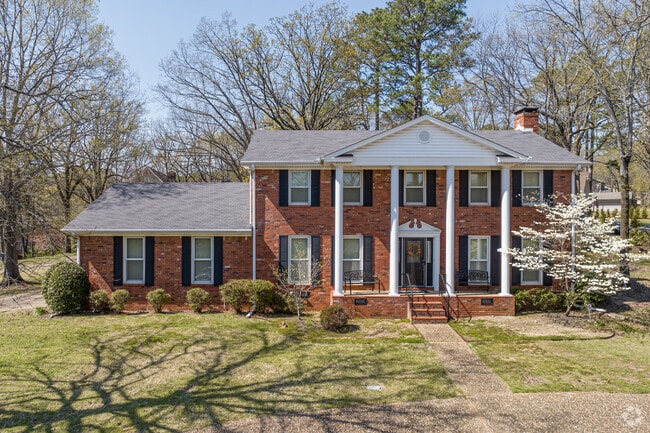 A red brick colonial home nestled in the trees of the Rock Creek neighborhood.