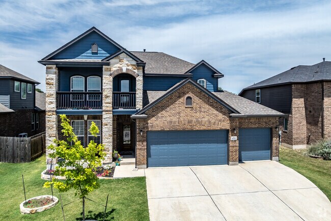 This brick and stone faced new traditional home has a 3-car garage in Blanco River District.