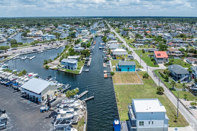 A view of Gulf Coast acres from above showcases docks full of boats, finger piers, and surrounding waterfront infrastrucate.