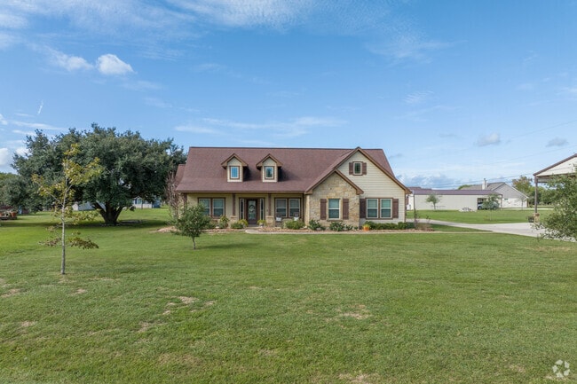 An updated ranch-style home fronts a large green lawn in Danbury, Texas.
